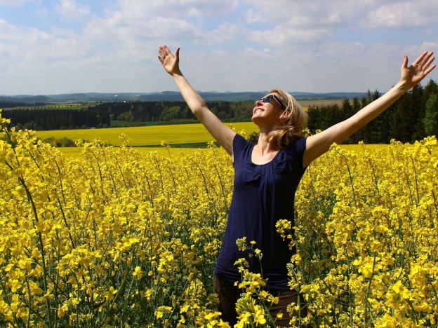 Frau auf Blumenfeld ist voller Dankbarkeit zu Gott